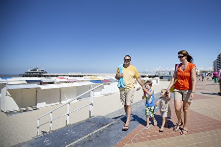 Family with children walking along the seaside promenade during summer