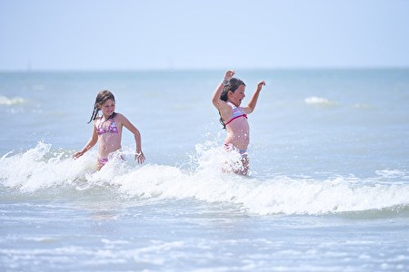 Two girls are playing in the surf of the sea
