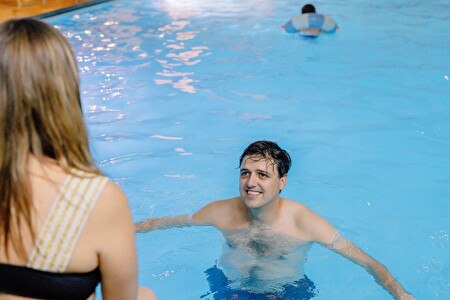 man in the water with woman on the edge of the bath