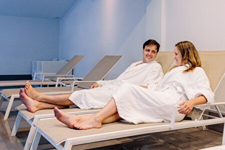 Couple in bathrobes on lounge chair next to the pool